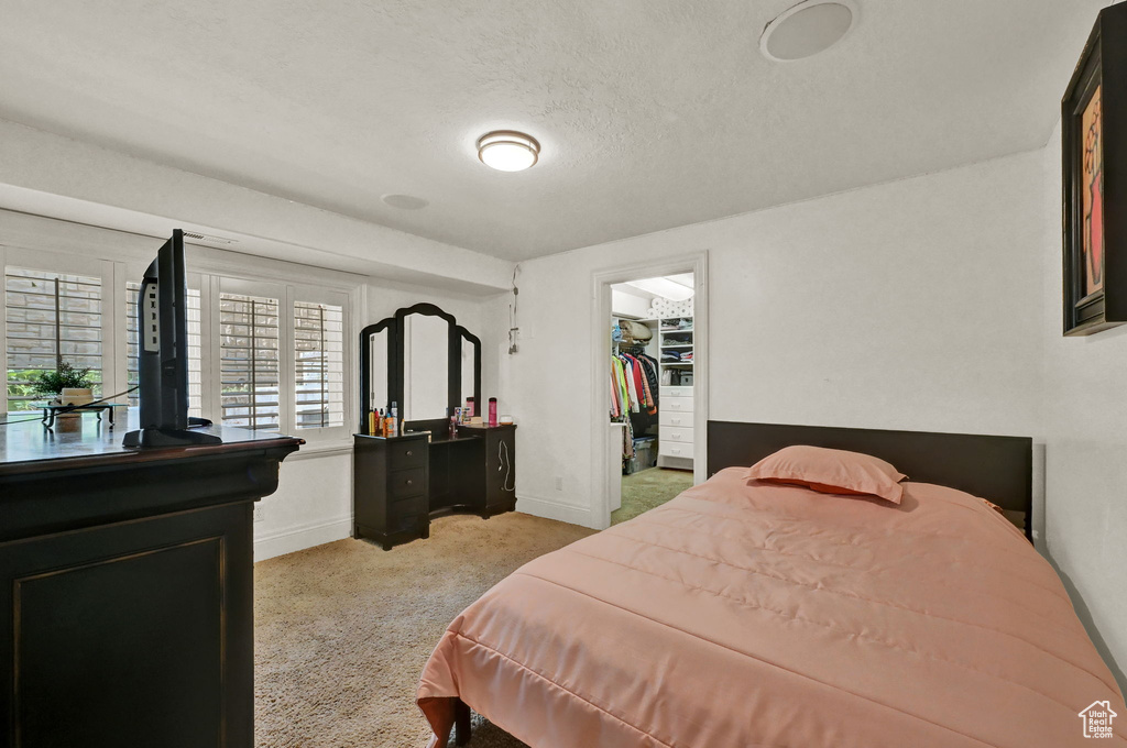 Carpeted bedroom featuring a textured ceiling, a closet, and a walk in closet