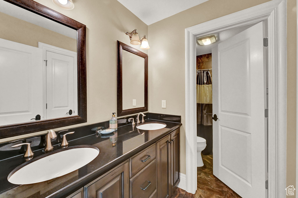 Bathroom with tile patterned floors, double vanity, and toilet