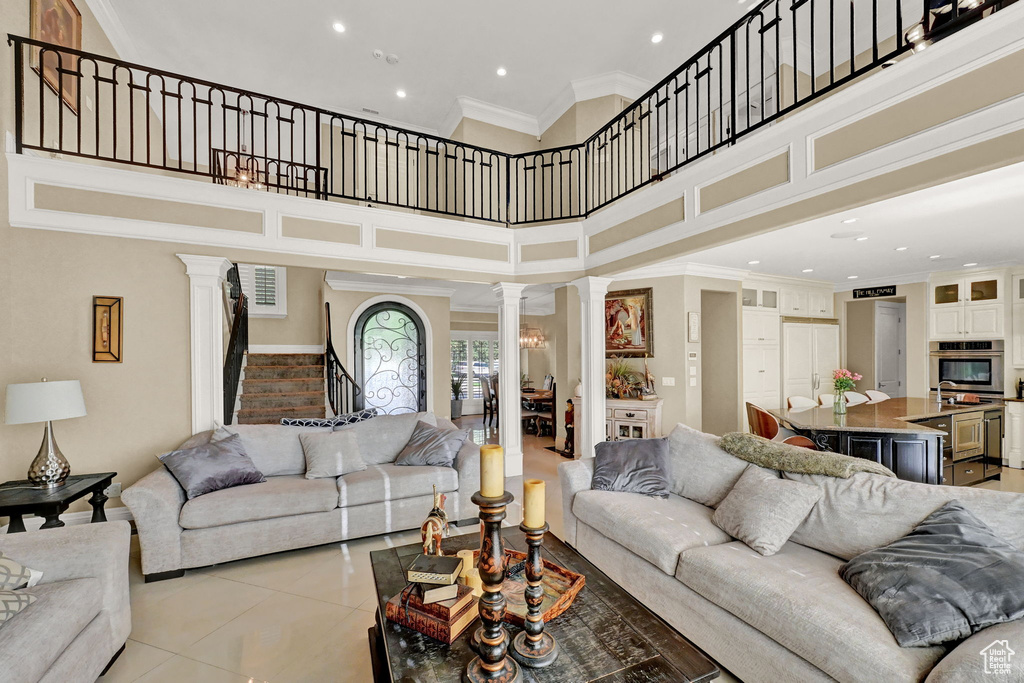 Tiled living room with crown molding, ornate columns, and a towering ceiling