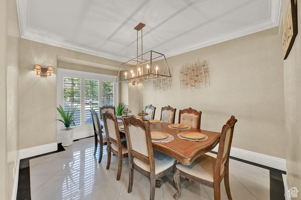 Dining space with light tile patterned floors, crown molding, and a chandelier