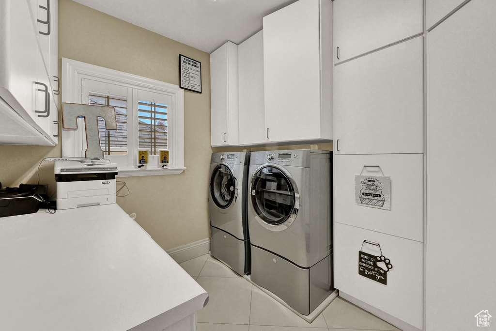 Laundry area with cabinets, light tile patterned flooring, and washing machine and dryer