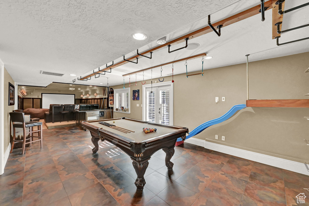 Rec room with dark tile patterned floors, bar, french doors, and billiards