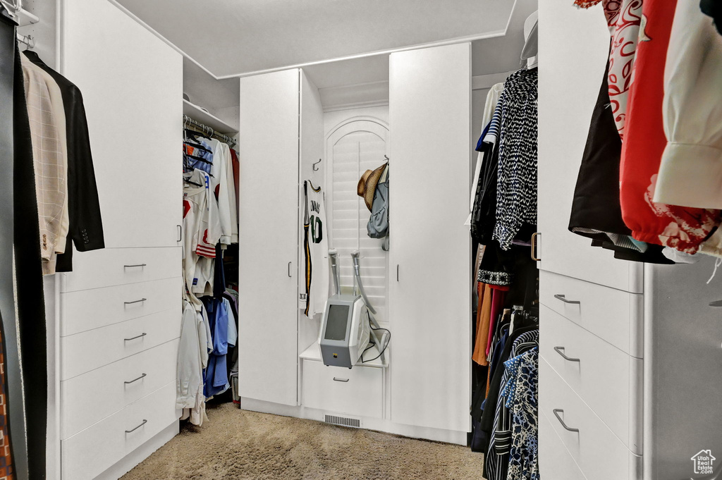 Walk in closet with light colored carpet