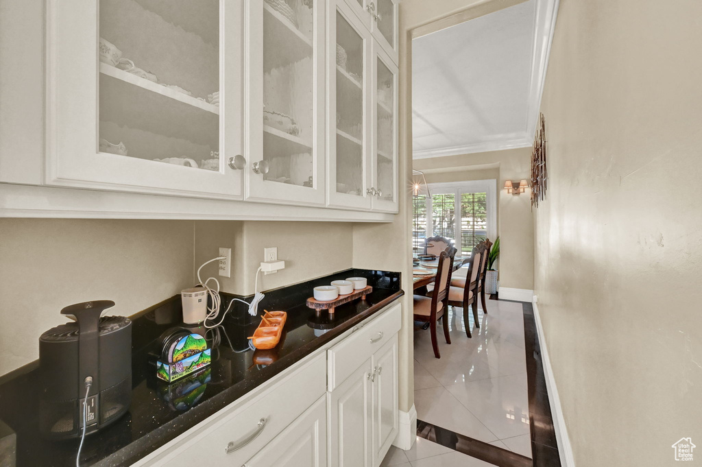 Bar with light tile patterned flooring, crown molding, and white cabinetry