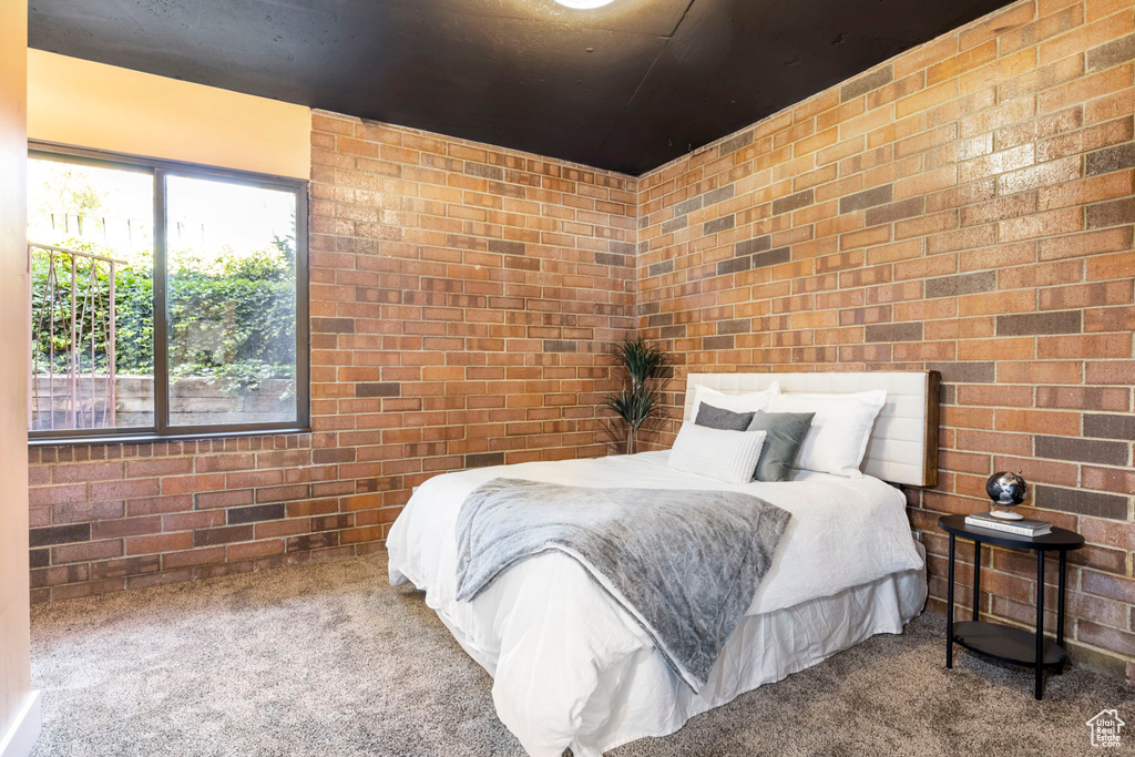 Carpeted bedroom featuring brick wall