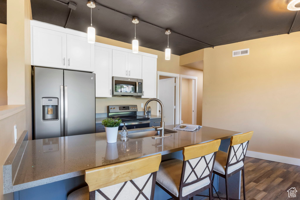 Kitchen with white cabinets, dark wood-type flooring, appliances with stainless steel finishes, and sink