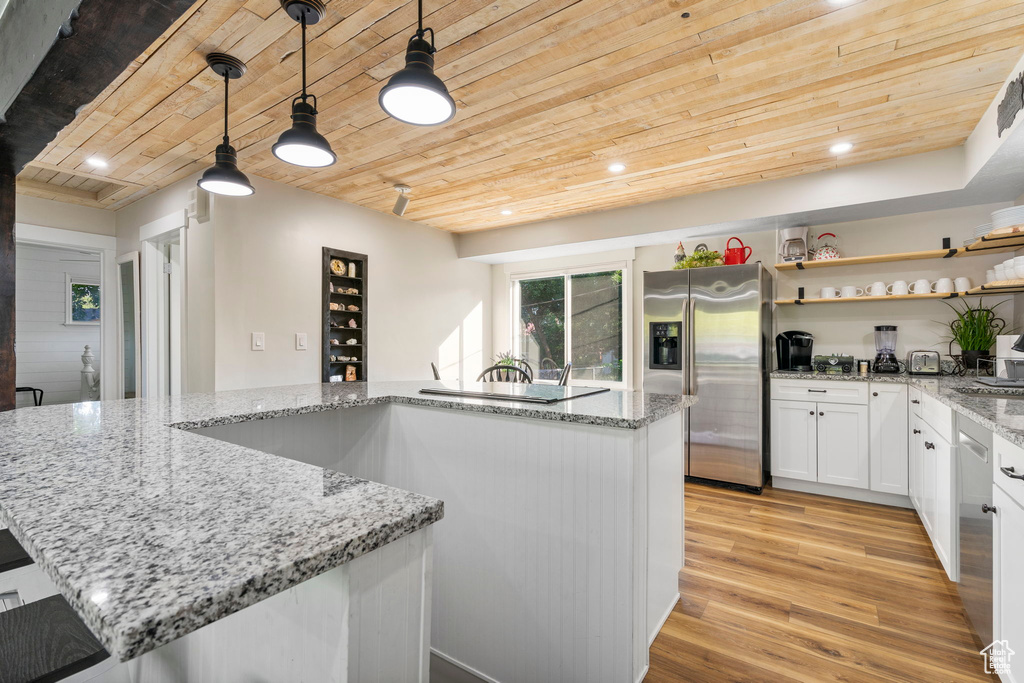 Kitchen featuring wood ceiling, light hardwood / wood-style floors, decorative light fixtures, stainless steel fridge with ice dispenser, and white cabinetry