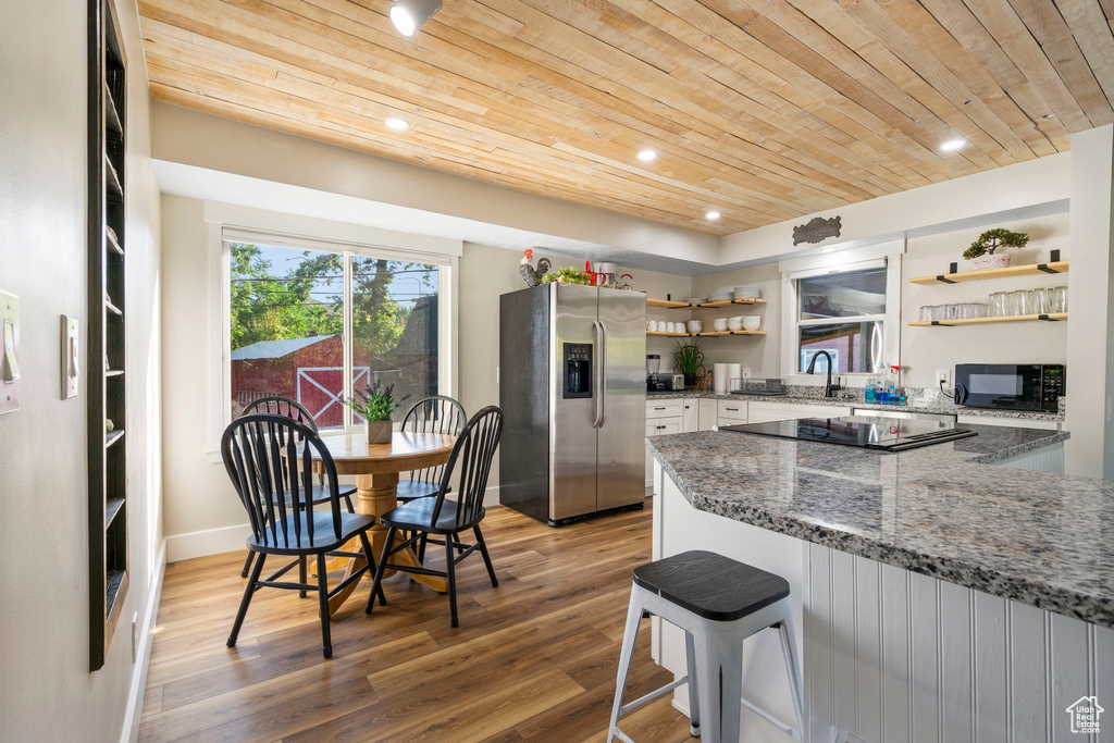 Kitchen featuring dark stone countertops, wood ceiling, wood-type flooring, and black appliances