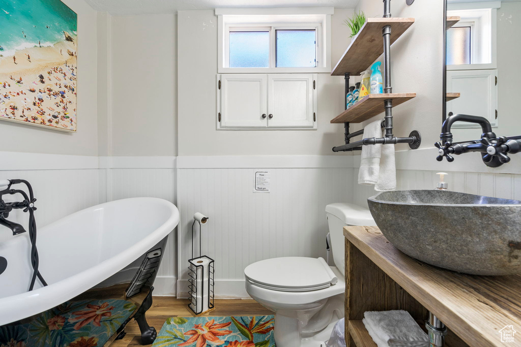 Bathroom with toilet, a bathing tub, hardwood / wood-style floors, and sink