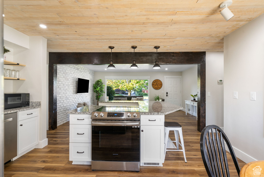 Kitchen featuring white cabinetry, a breakfast bar area, hardwood / wood-style floors, and stainless steel appliances