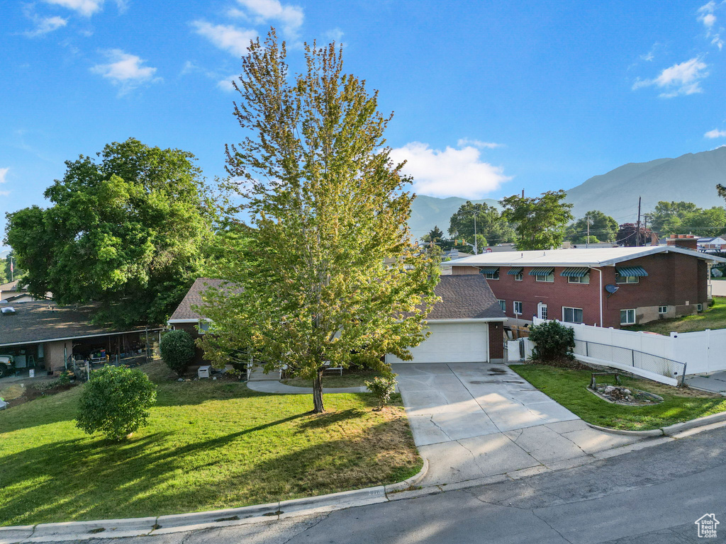 View of front of home featuring a garage, a mountain view, and a front yard