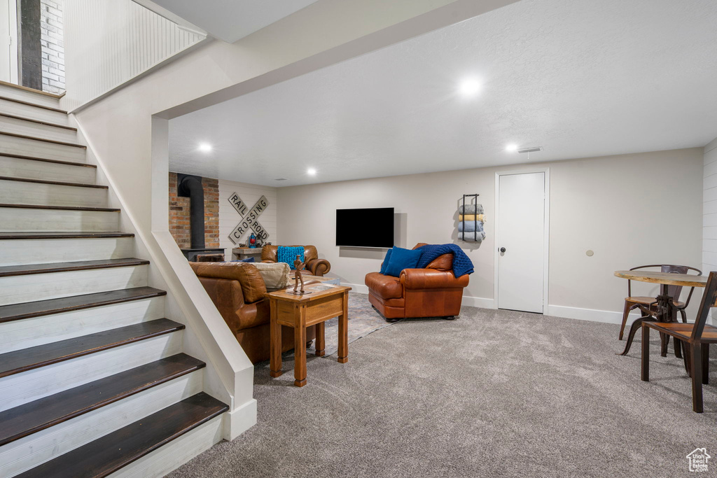 Carpeted living room with brick wall and a wood stove