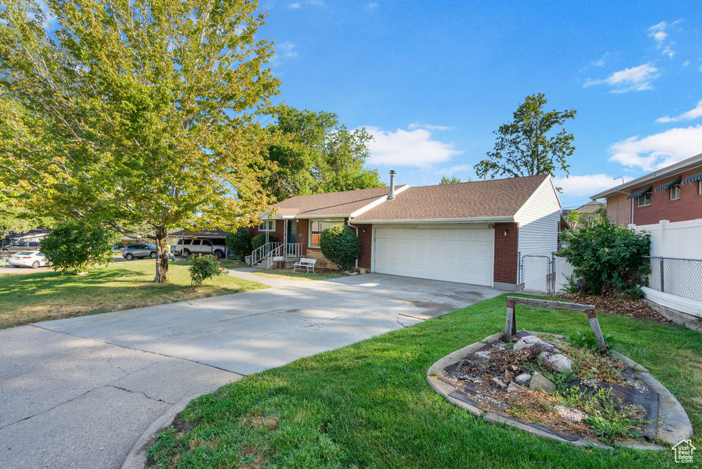 Single story home featuring a garage and a front lawn