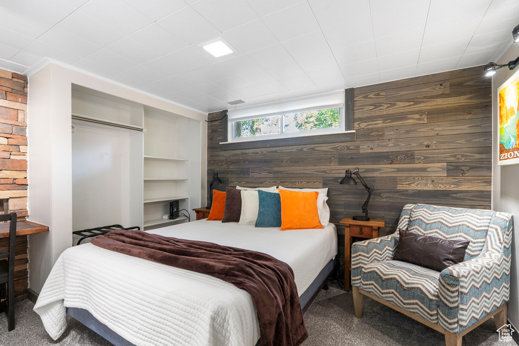 Bedroom featuring carpet floors, wood walls, and a closet