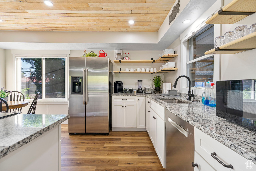 Kitchen with light hardwood / wood-style flooring, stainless steel appliances, wood ceiling, sink, and white cabinetry