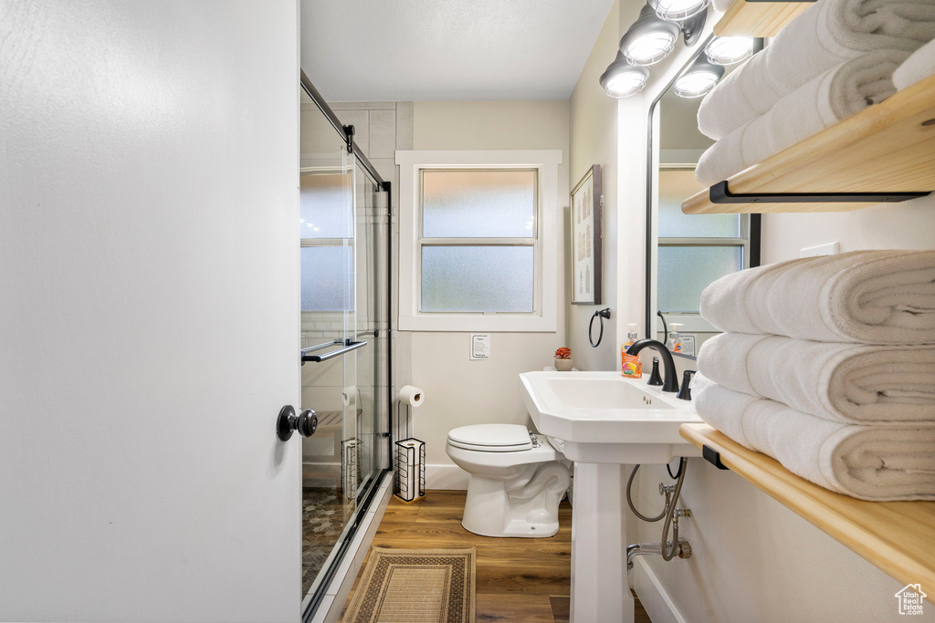 Bathroom featuring toilet, a shower with door, a healthy amount of sunlight, and hardwood / wood-style floors