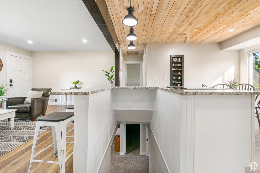 Interior space with light stone counters, wooden ceiling, decorative light fixtures, and light colored carpet