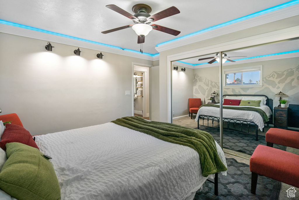 Bedroom with a closet, ceiling fan, crown molding, and carpet floors