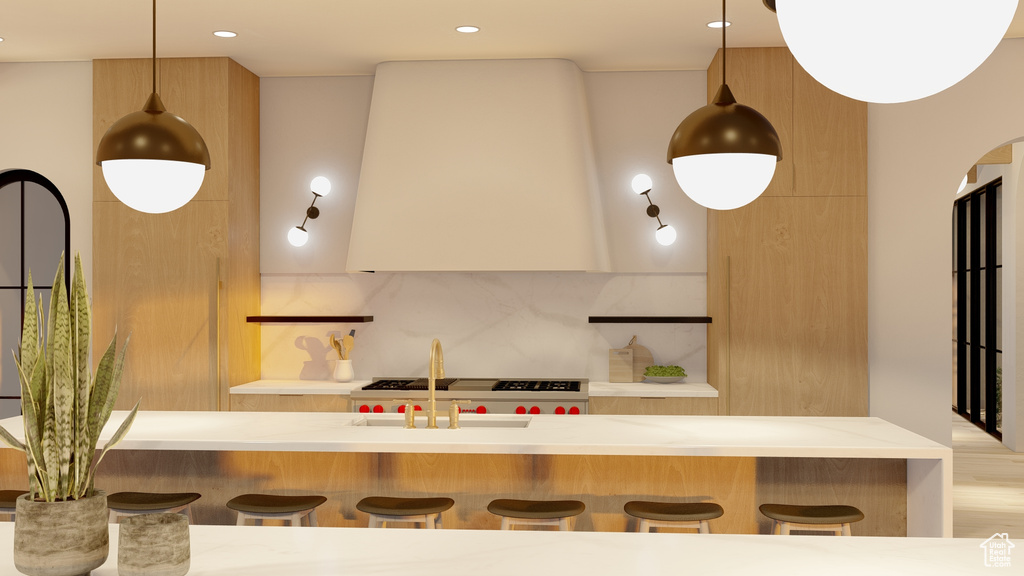 Kitchen featuring range, a breakfast bar area, pendant lighting, backsplash, and light hardwood / wood-style floors