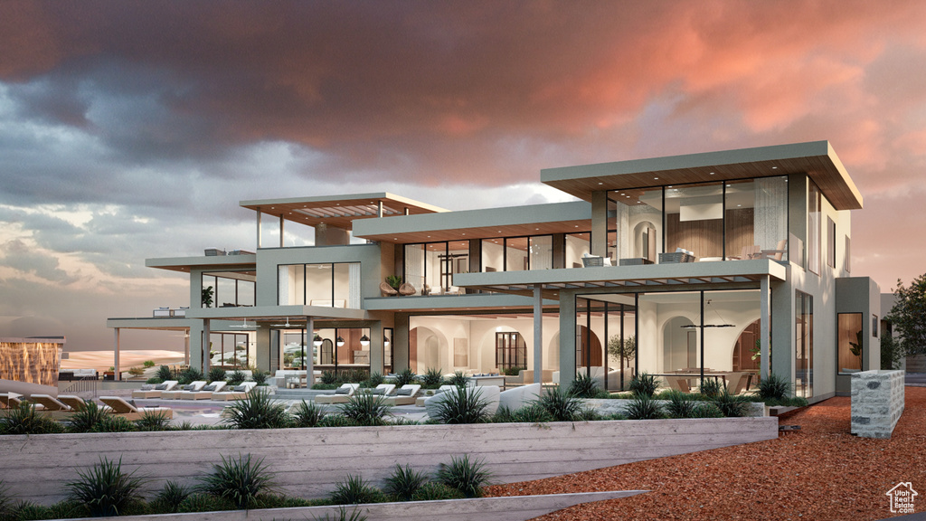 Back house at dusk featuring a balcony