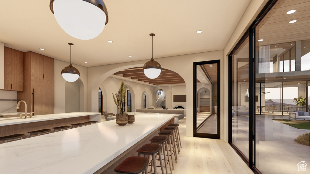 Kitchen featuring sink, light wood-type flooring, hanging light fixtures, and a breakfast bar