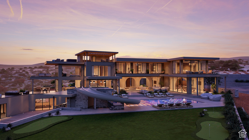 Back house at dusk featuring a patio and a balcony