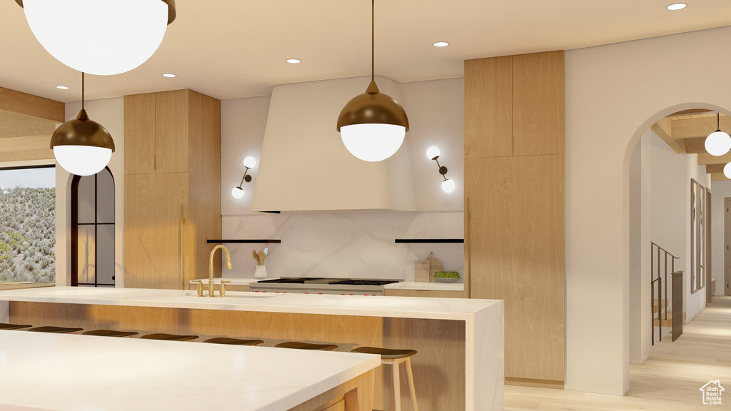 Kitchen featuring a breakfast bar, hanging light fixtures, light wood-type flooring, and backsplash