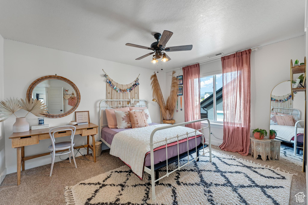 Carpeted bedroom featuring a textured ceiling and ceiling fan