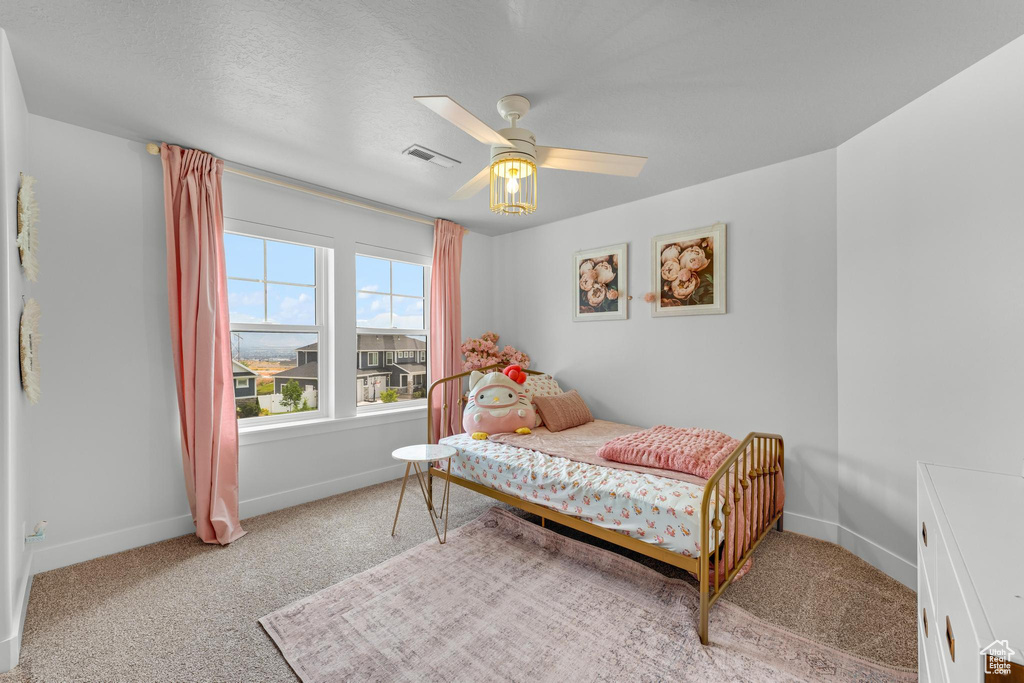 Bedroom with a textured ceiling, ceiling fan, and light colored carpet