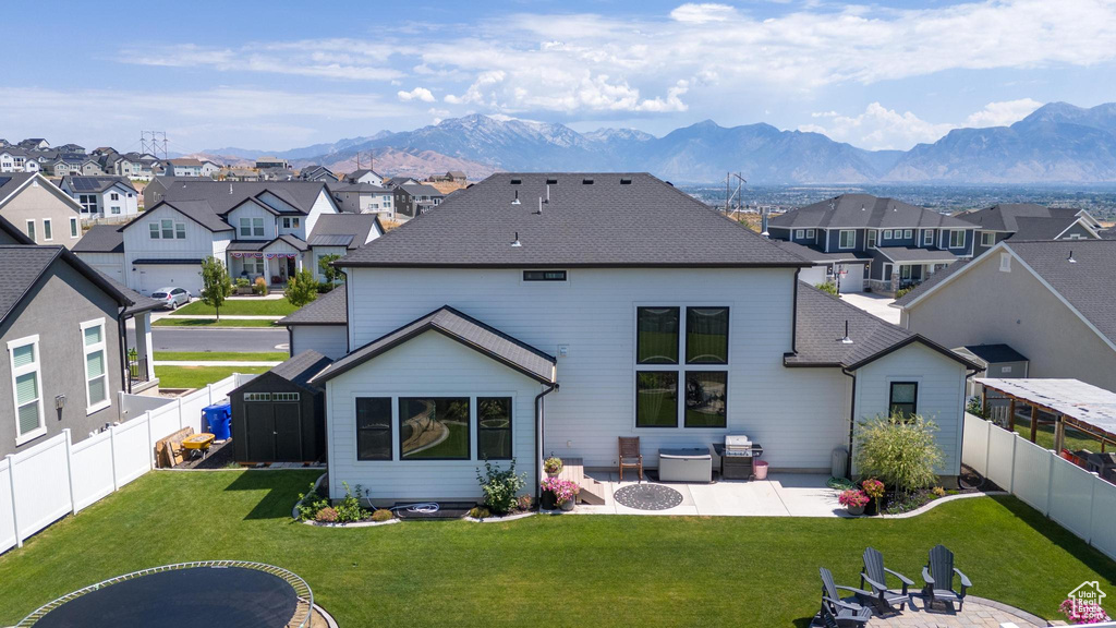 Rear view of house with a mountain view, a patio area, a lawn, and an outdoor fire pit