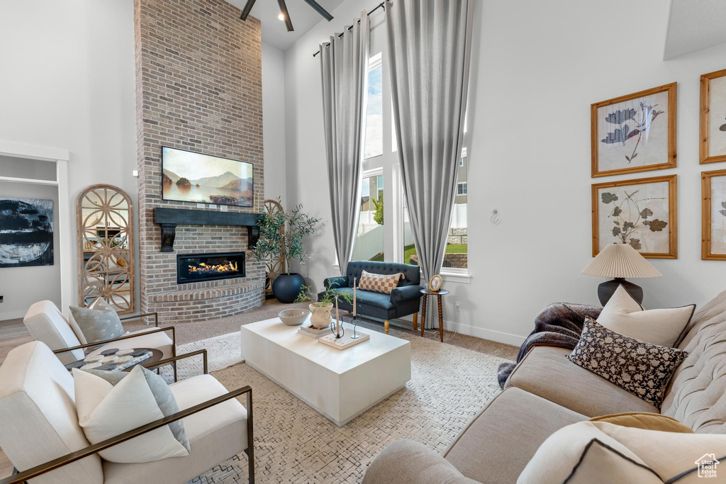 Living room featuring a high ceiling, a brick fireplace, and a healthy amount of sunlight