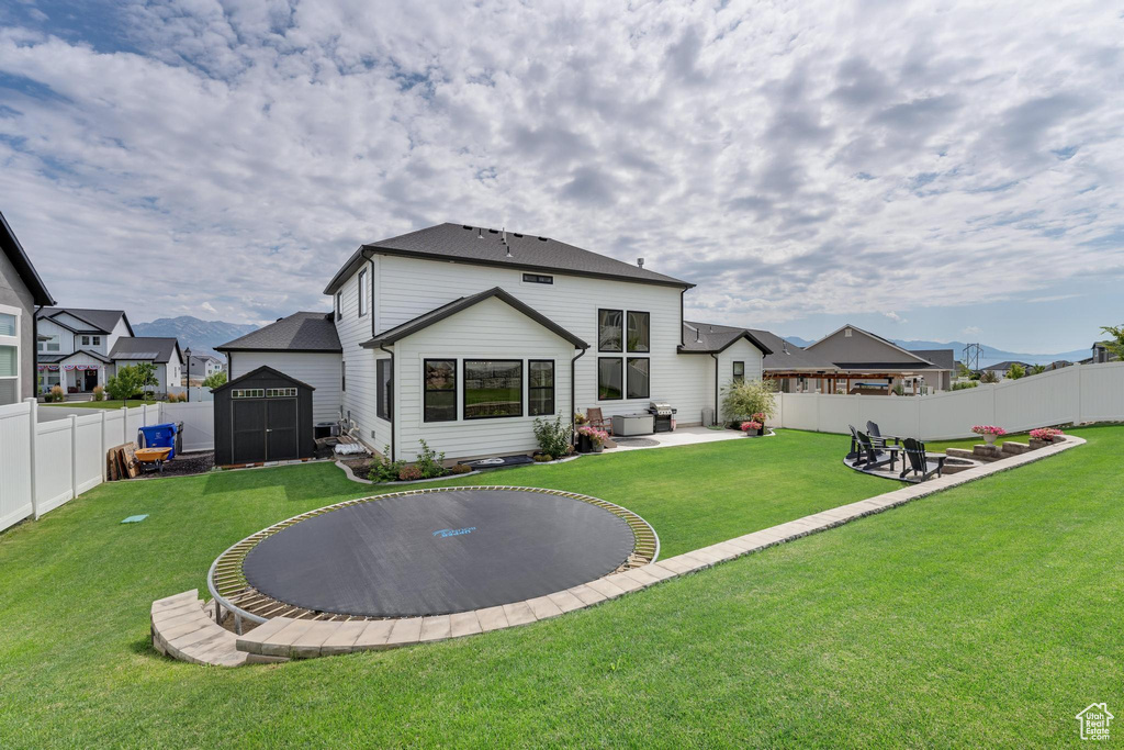 Back of house featuring a storage shed, a patio, and a lawn