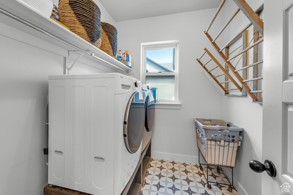 Clothes washing area featuring light tile patterned flooring and washer and dryer