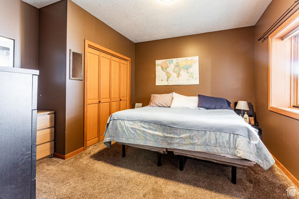 Bedroom with light carpet, a closet, and a textured ceiling