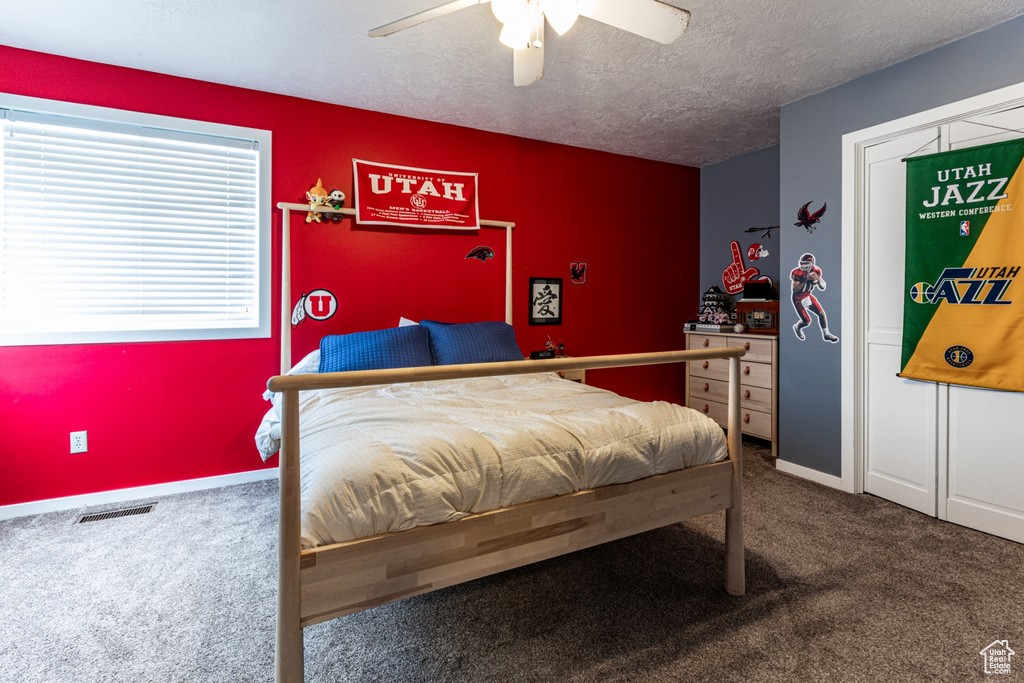 Carpeted bedroom featuring a textured ceiling and ceiling fan