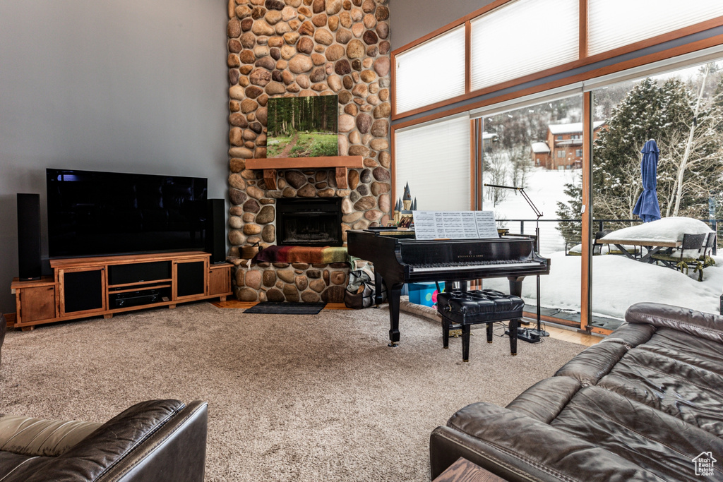 Carpeted living room featuring a fireplace and a high ceiling