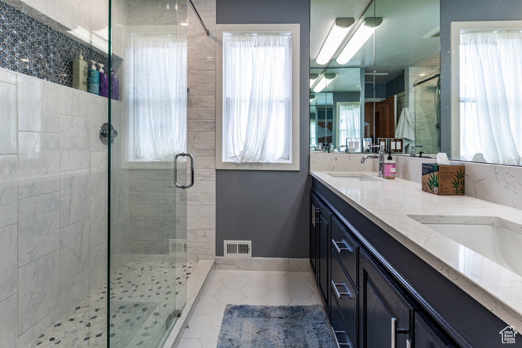 Bathroom with walk in shower, tile patterned floors, and dual bowl vanity