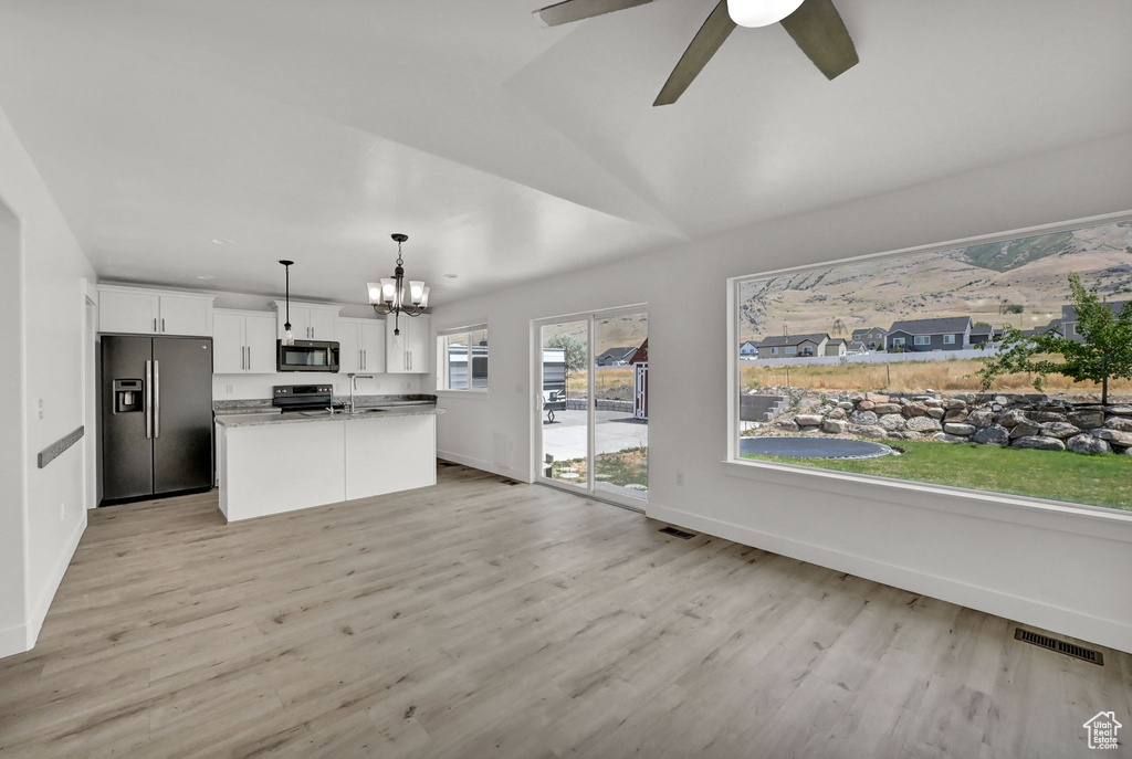 Kitchen with decorative light fixtures, white cabinets, an island with sink, light hardwood / wood-style floors, and refrigerator with ice dispenser