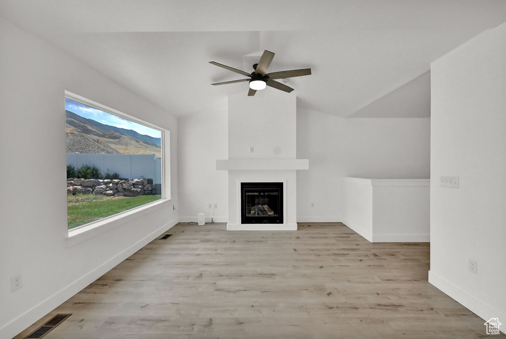 Unfurnished living room with lofted ceiling, light wood-type flooring, and ceiling fan