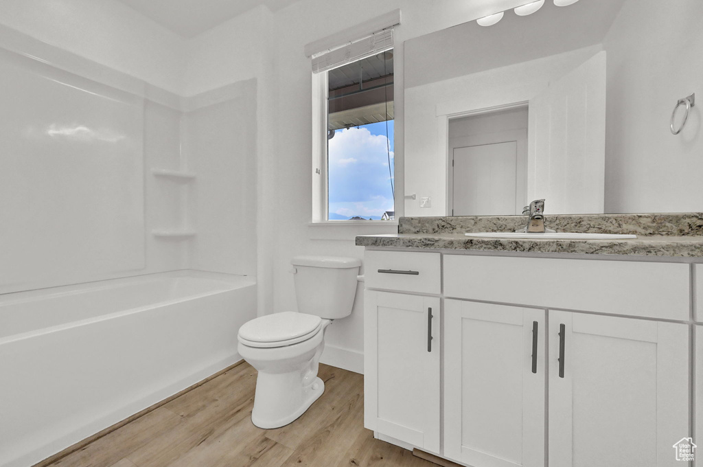 Full bathroom featuring vanity, toilet, wood-type flooring, and tub / shower combination