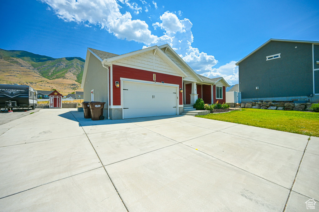 View of front of property featuring a garage, a front lawn, and a mountain view