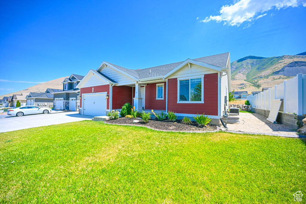 View of front of house with a garage, a mountain view, and a front yard