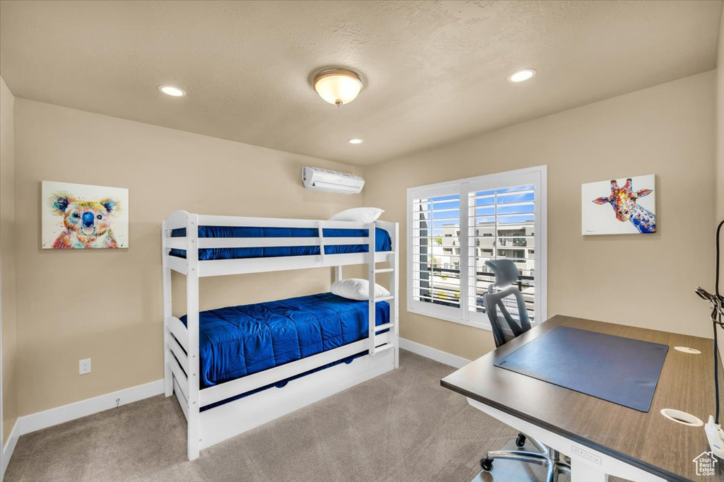 Bedroom with an AC wall unit and light carpet