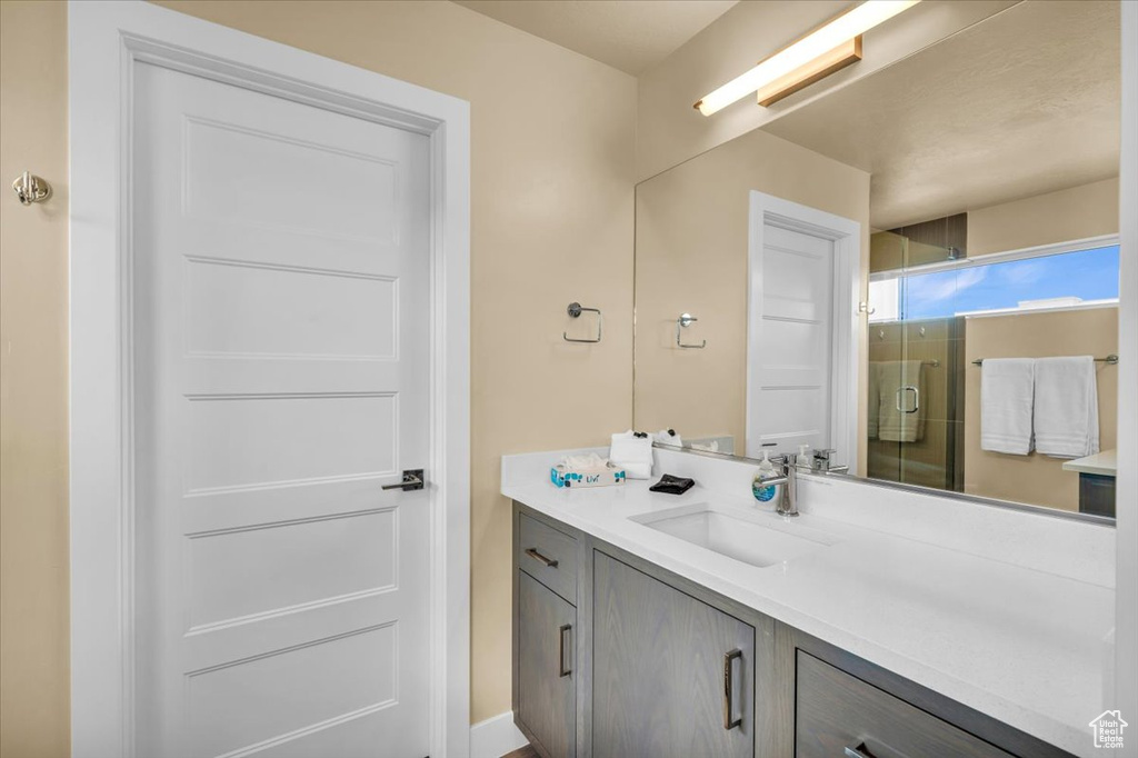 Bathroom featuring a shower with shower door and vanity