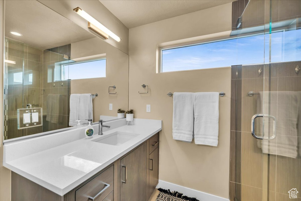 Bathroom featuring a shower with shower door and vanity