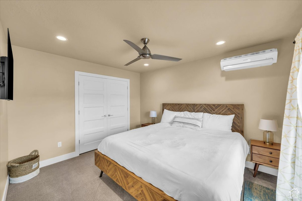 Carpeted bedroom with a wall mounted AC, a closet, and ceiling fan