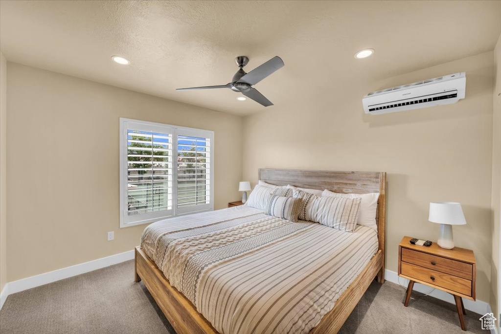 Carpeted bedroom with an AC wall unit and ceiling fan