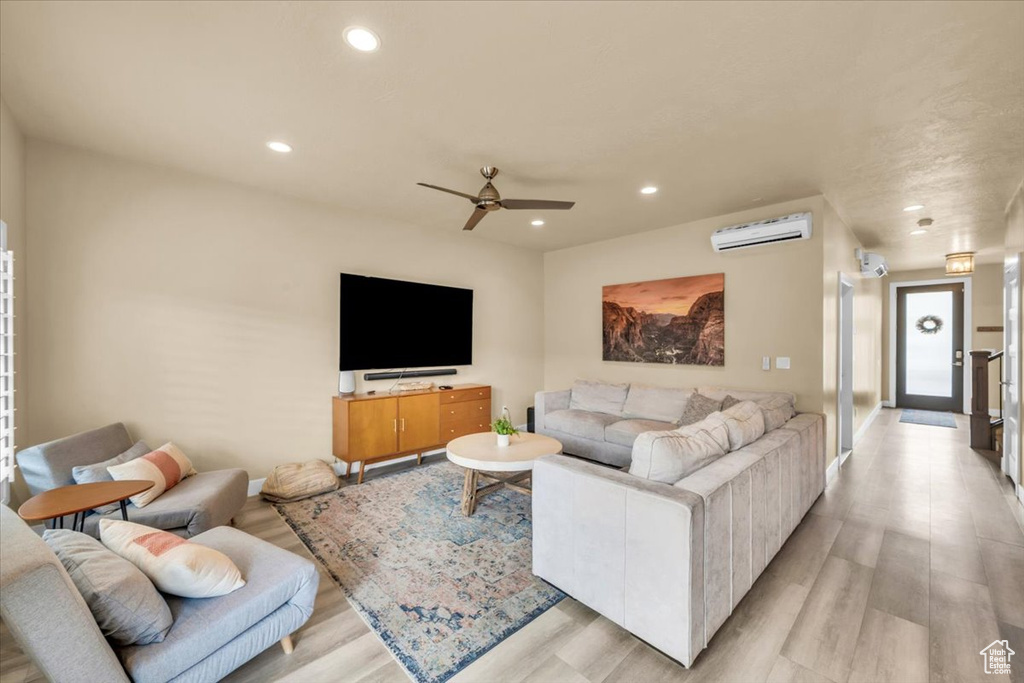 Living room featuring light hardwood / wood-style floors, a wall mounted air conditioner, and ceiling fan