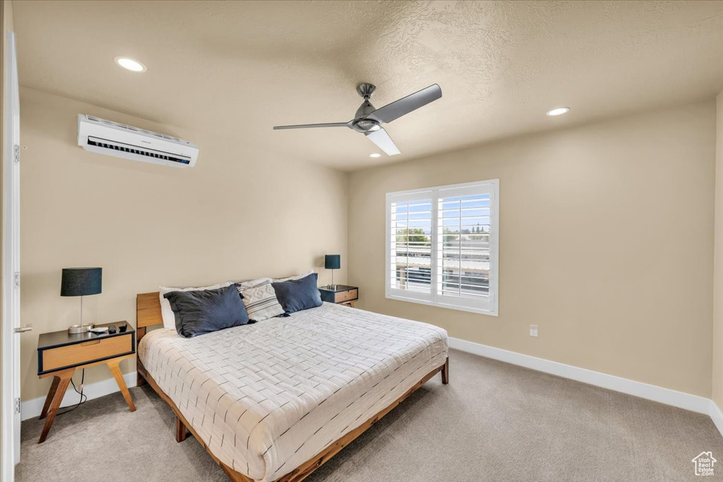 Carpeted bedroom with a wall unit AC and ceiling fan