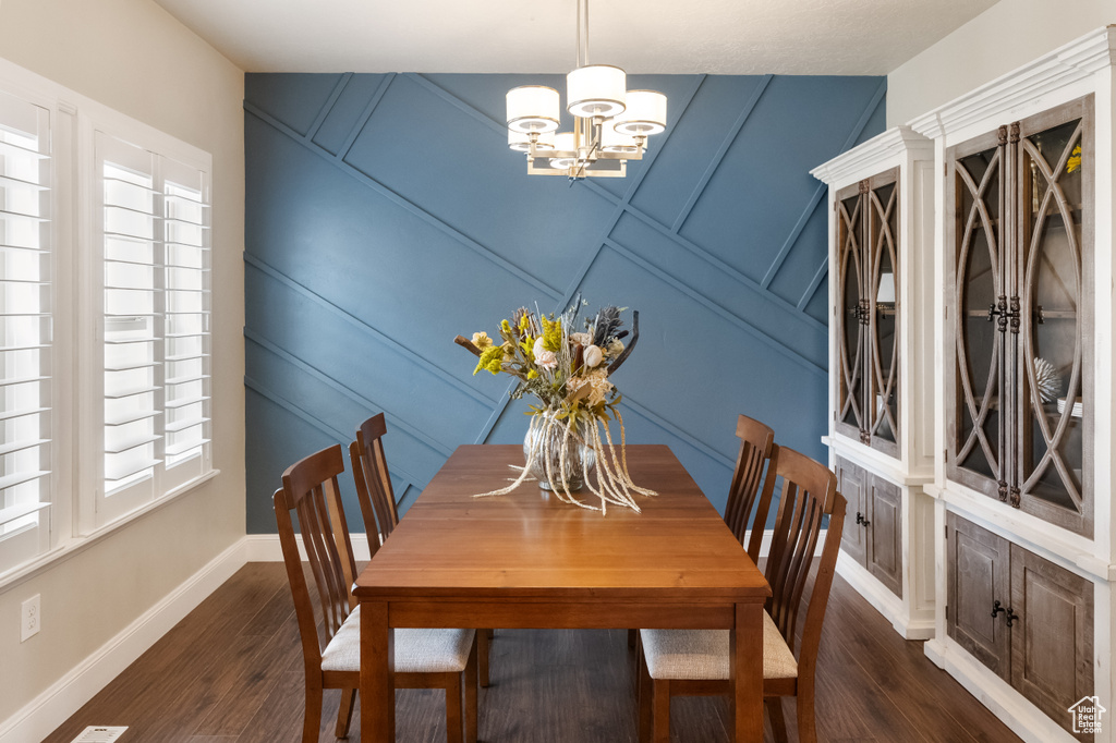 Dining space with dark hardwood / wood-style floors and a chandelier